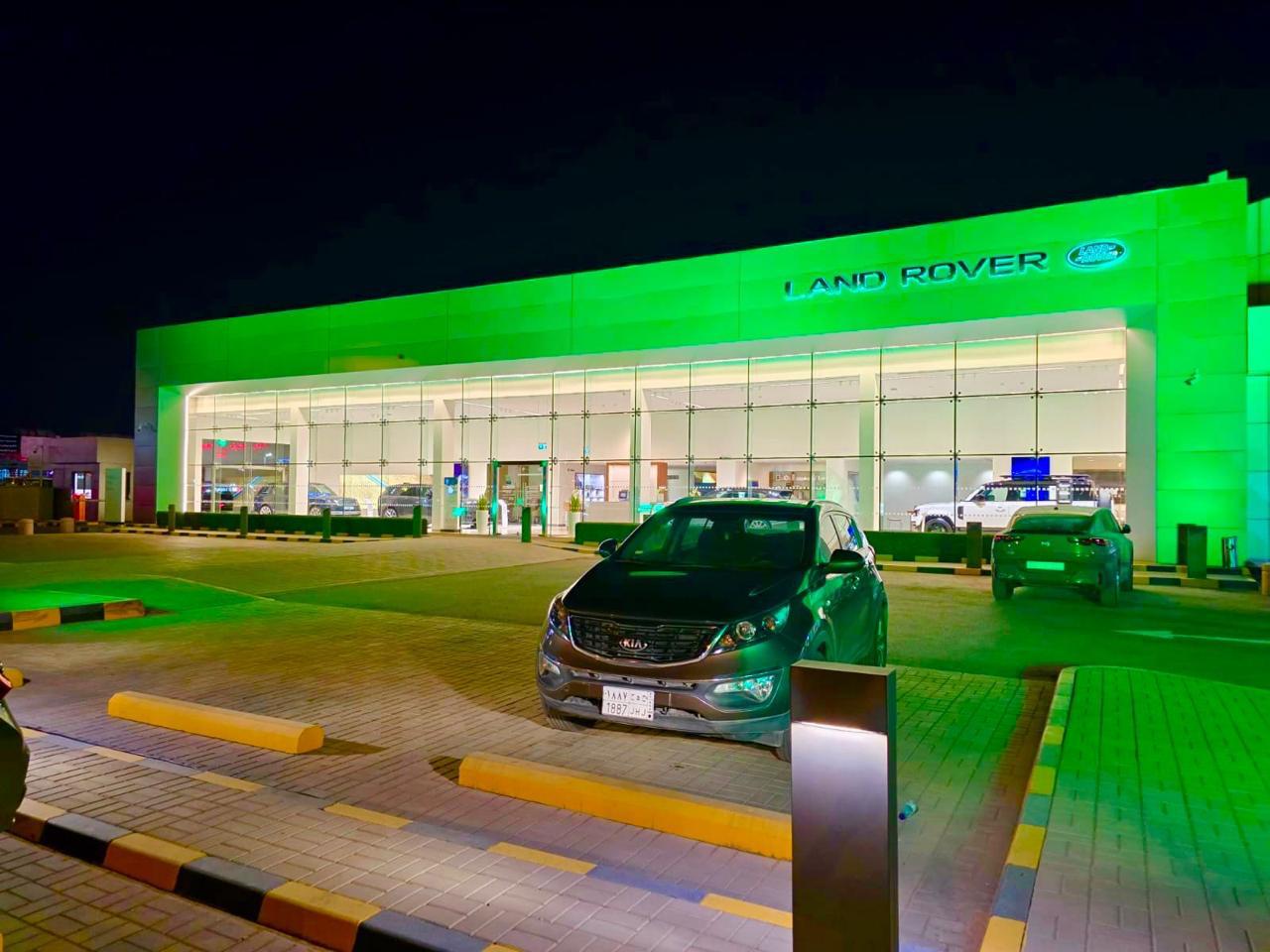 Land Rover showroom facade lit green for Saudi National Day at Mohamed Yousuf Naghi Motors.