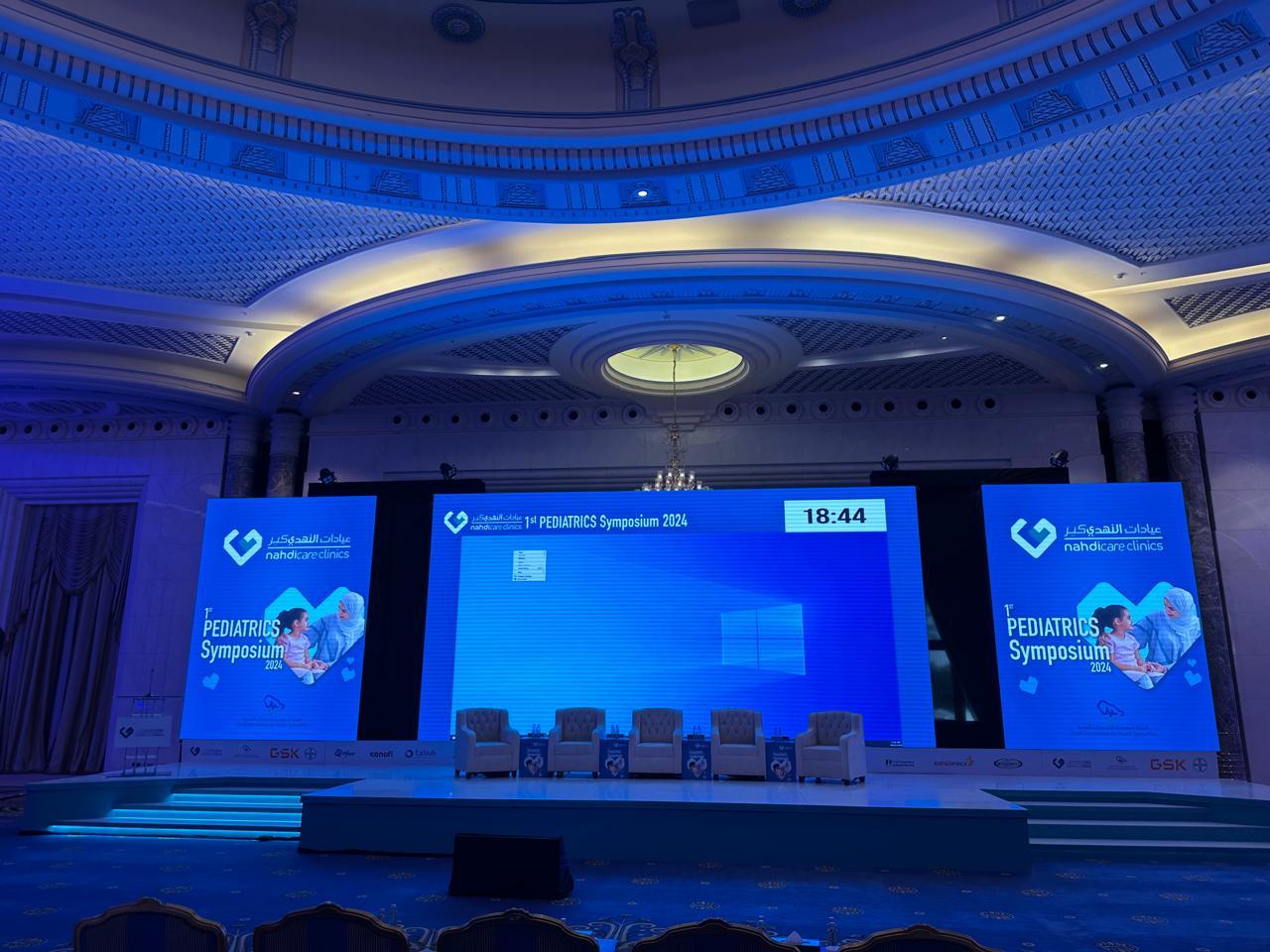Nahdi Care Pediatrics Symposium stage and presentation screens in Riyadh.