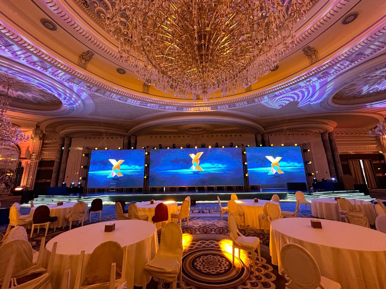 Triple-screen gala stage set in a chandeliered ballroom for an awards night.