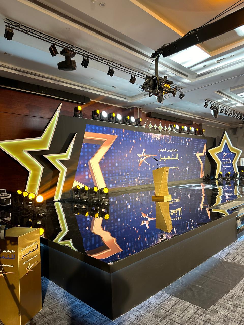 Award stage with sculpted lit stars reflected in a mirrored floor.